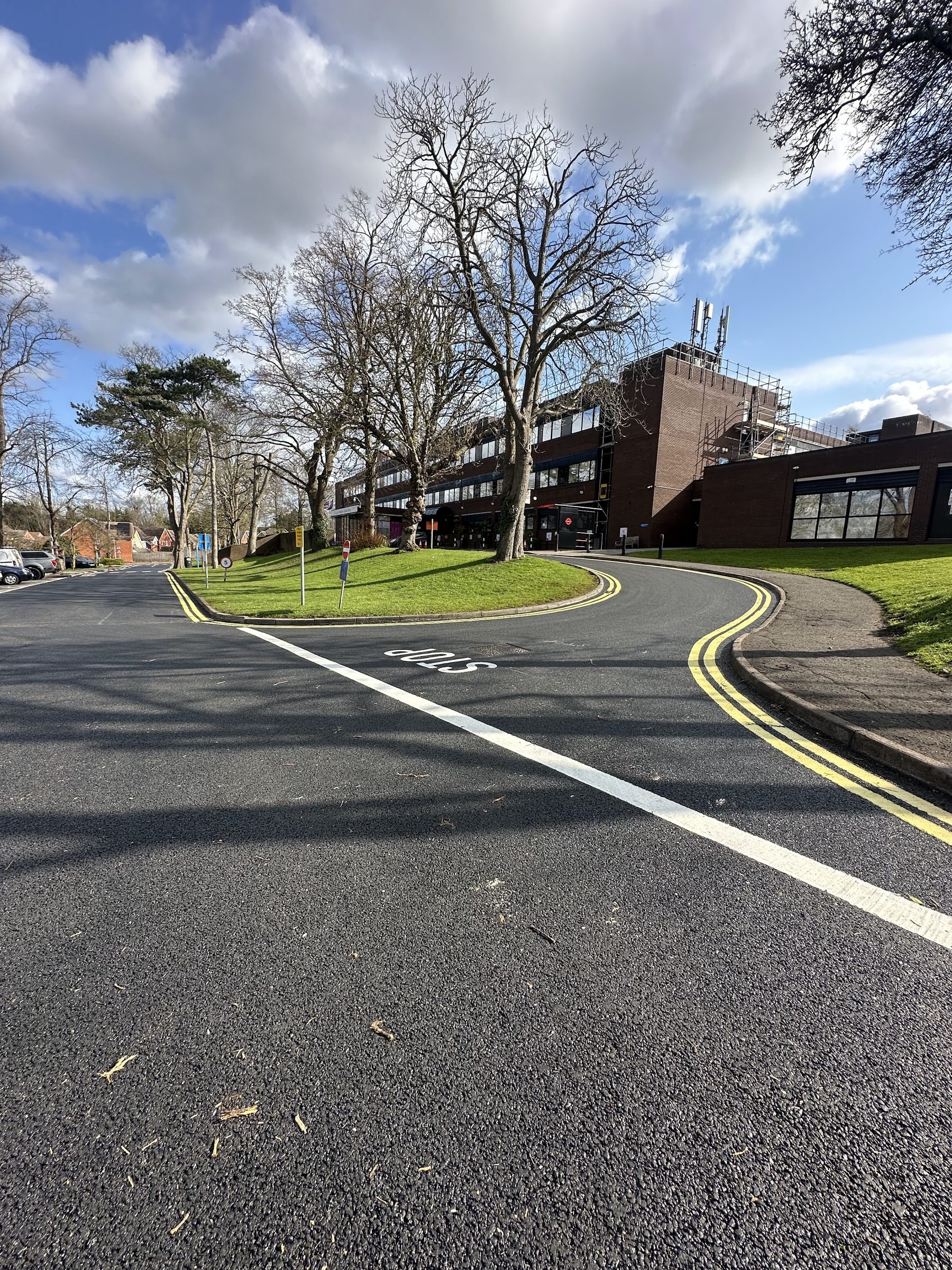 Newly resurfaced road with white STOP marking and double yellow lines at Orpington Hospital